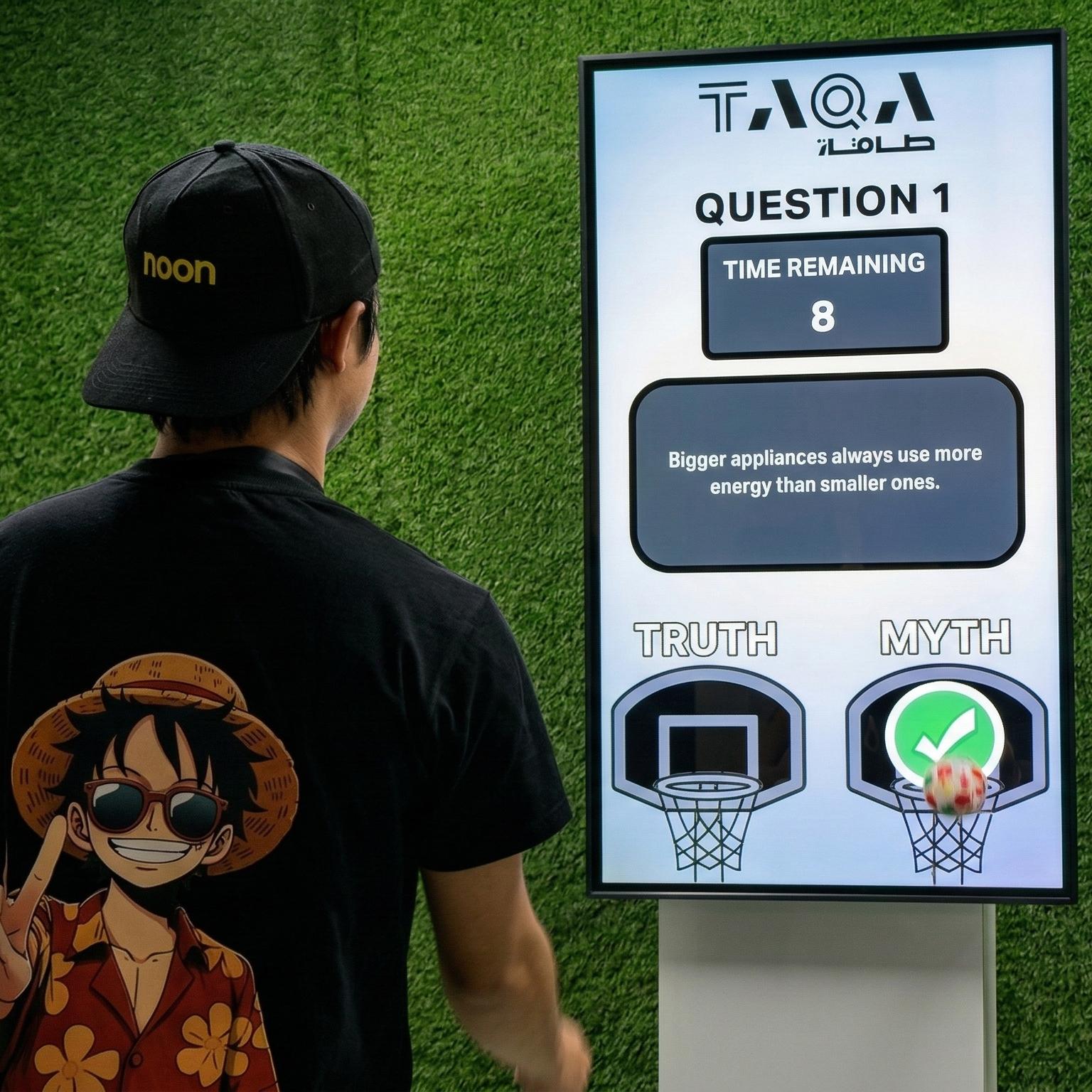 A guest throwing a softball at a large digital Truth or Myth display screen to lock in an answer at a high-energy corporate exhibition booth activation